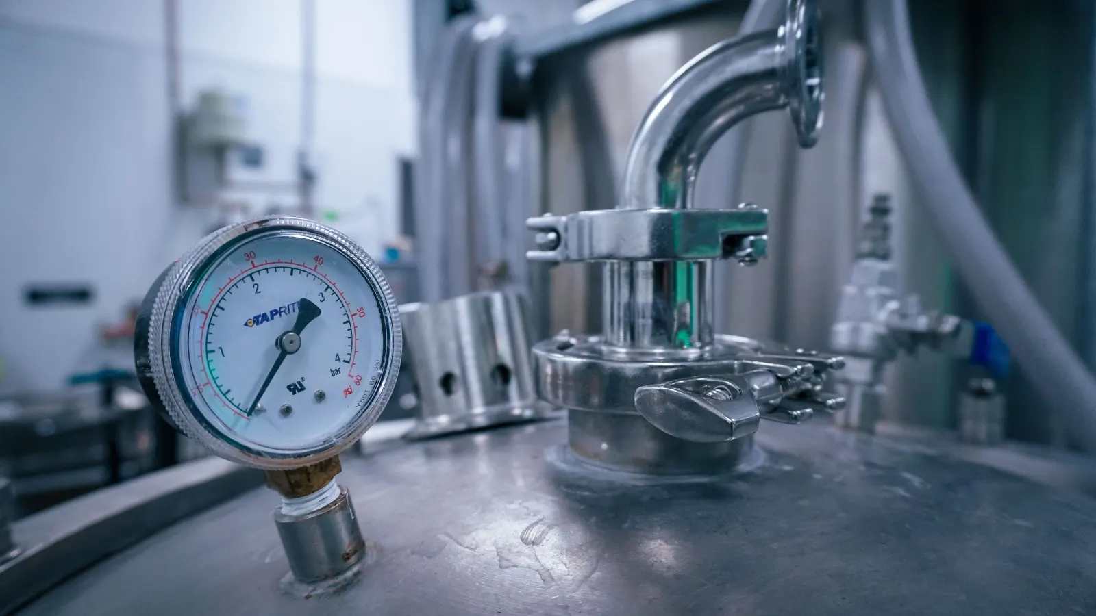 Analog pressure gauge mounted on a polished stainless steel industrial tank